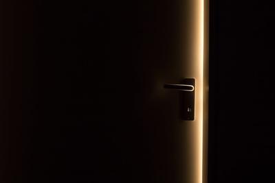 Door in a dark room, ajar. Light coming from beyond the door.
